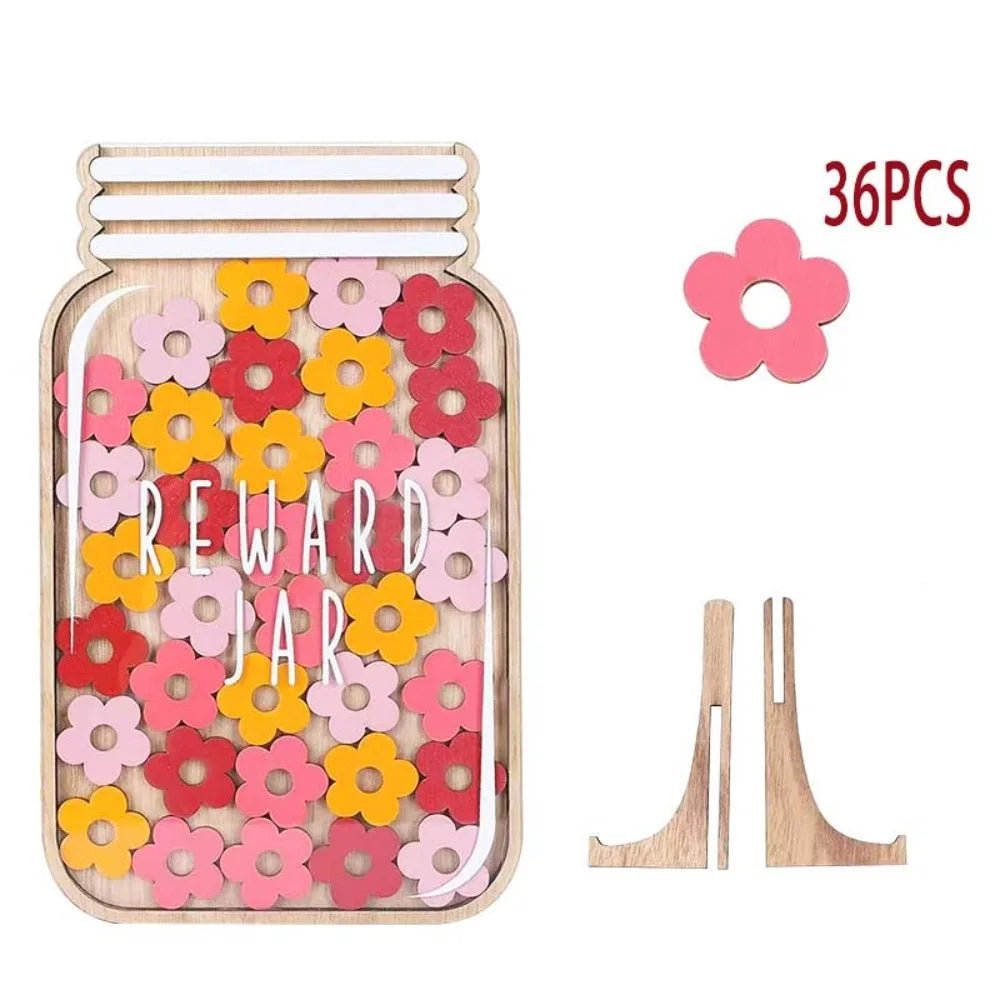 A wooden reward jar filled with pink and orange flowers and two wooden tweezers.