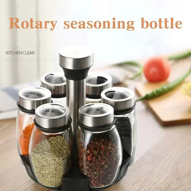 A set of rotating glass spice jars with a rack, showing various dried spices like pepper and herbs.