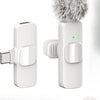 A white wireless lavalier microphone with a fluffy gray windscreen and a rectangular body is shown.