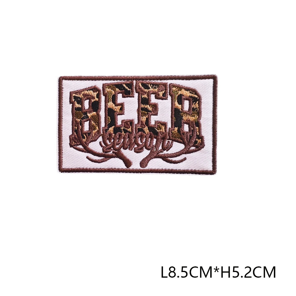 A brown embroidered patch featuring the word BEER with leafy vines.