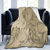 A beige map of Middle Earth is displayed as a fade-resistant plush throw blanket draped over a dark sofa.