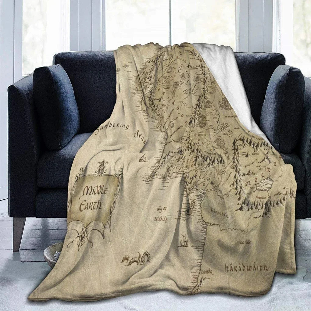 A beige map of Middle Earth is displayed as a fade-resistant plush throw blanket draped over a dark sofa.