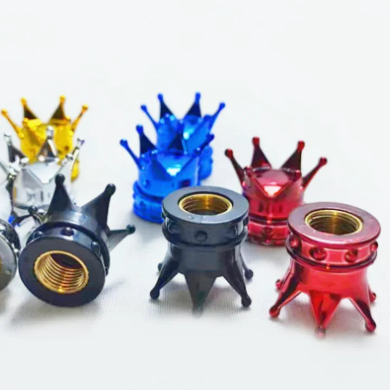 A set of four universal crown valve caps in gold, blue, and red metal finishes displayed on a white background.