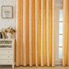Floor-length peach gold blackout curtains with a feather jacquard pattern hanging in a light-colored room.