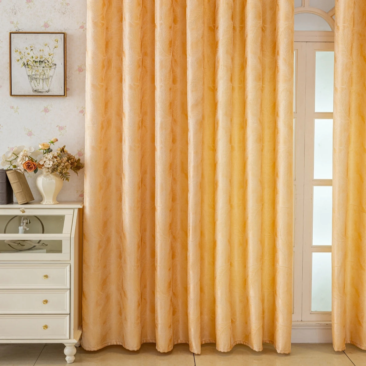 Floor-length peach gold blackout curtains with a feather jacquard pattern hanging in a light-colored room.