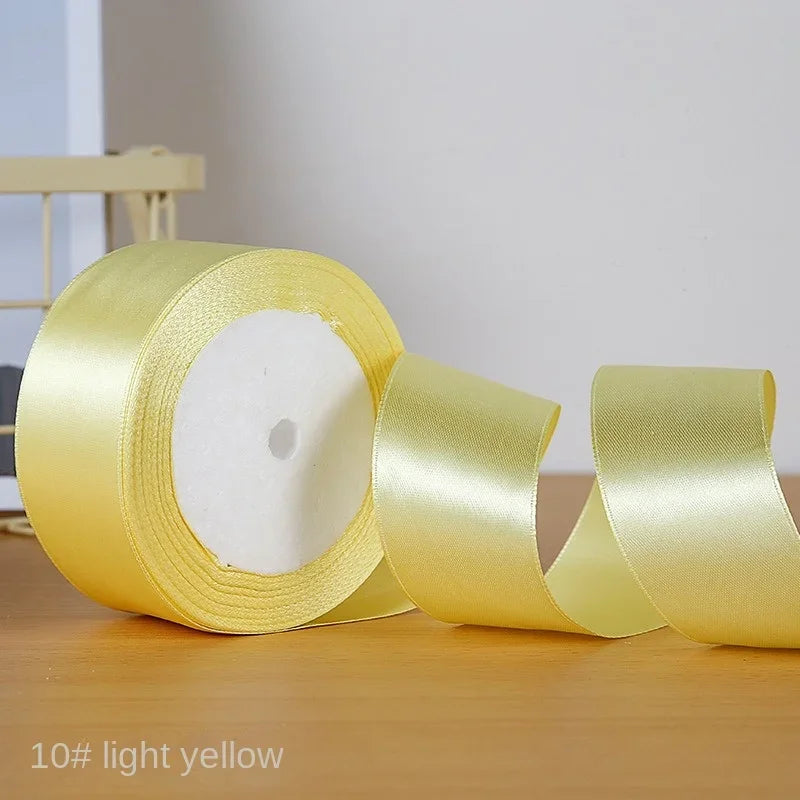 A roll of light yellow satin ribbon used for gift wrapping or DIY crafts.