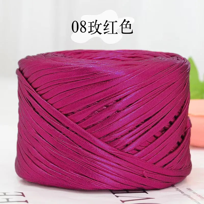 A magenta metallic flat ribbon yarn skein rolled into a cylinder.