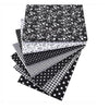 A stack of black and white cotton fabric squares featuring various patterns including floral, polka dot, striped, and checker