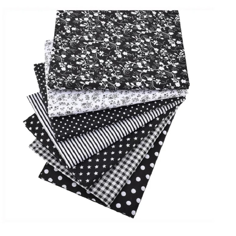 A stack of black and white cotton fabric squares featuring various patterns including floral, polka dot, striped, and checker