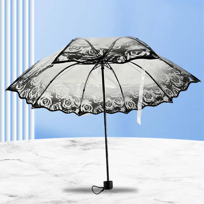A black umbrella with a transparent canopy featuring a floral design is shown against a light blue background.