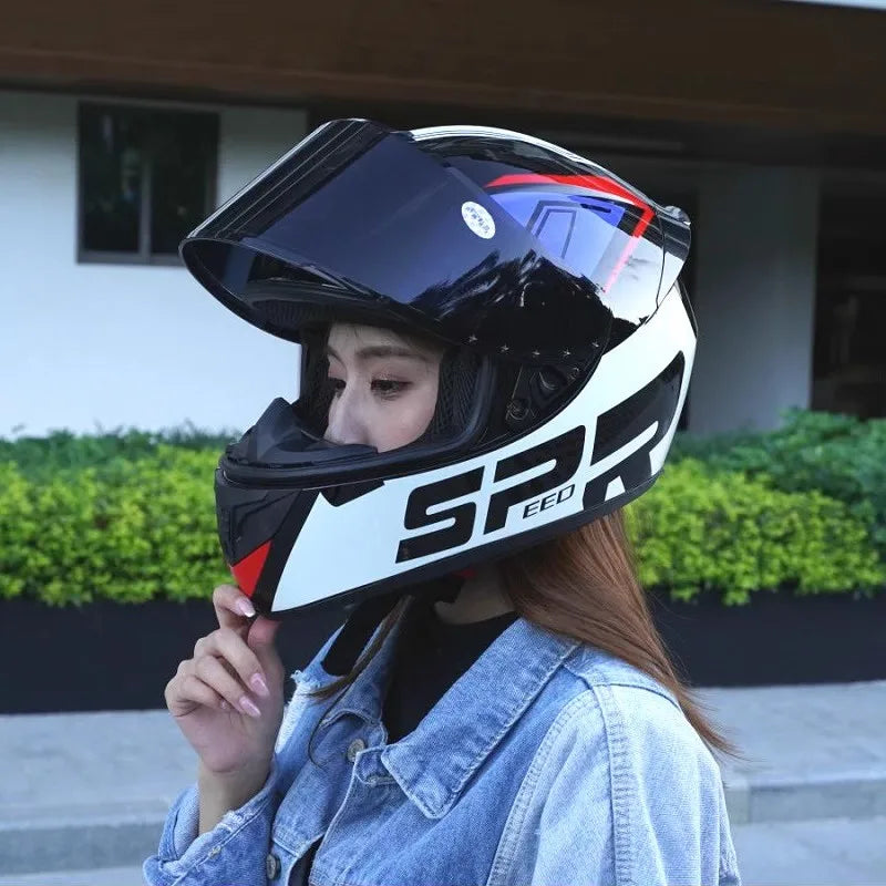 A woman wearing a black and white full-face motorcycle helmet with a clear visor and a denim jacket.