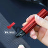 A hand is using a red emergency window breaker and seatbelt cutter tool against a dark fabric background.