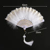 A white lace folding hand fan with a gold decorative edge and a long handle, shown against a black background.