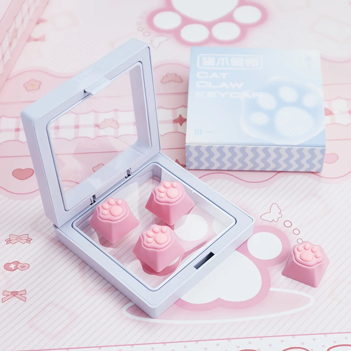 A clear plastic case holds pink silicone cat paw and heart keycaps for MX switches on a pink background.