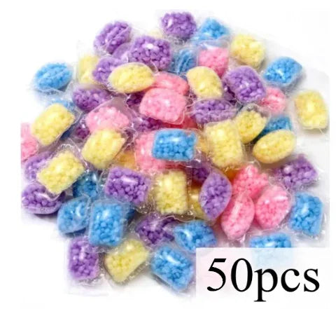 A pile of colorful water-soluble laundry fragrance beads in various shades of purple, blue, and yellow.