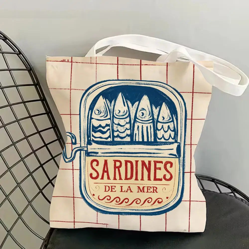 A canvas tote bag featuring a blue print of sardines on a red and white checkered background.