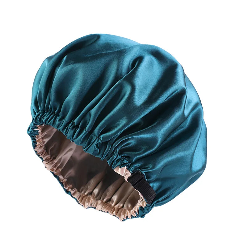 A teal satin sleep bonnet with a gathered edge, shown from the side.