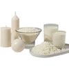 Natural soy wax granules displayed with candles and liquid in glass jars on a white tray