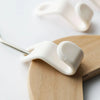 A close-up of a white space-saving cascading hanger connector hook being placed onto a wooden board.