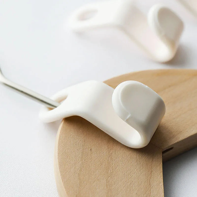 A close-up of a white space-saving cascading hanger connector hook being placed onto a wooden board.