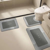 Three rectangular floor mats with the word HOME printed on them are placed in front of a white toilet.