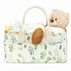 A cream-colored floral diaper organizer bag with multiple compartments, featuring a bear plush toy.