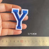 A hand holds a blue and white embroidered letter Y patch, measuring 5.1 by 3.9 cm against a ruler.