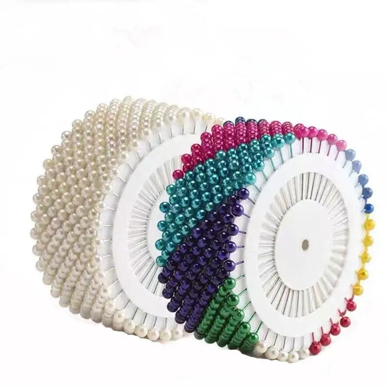 A collection of colorful round pearl straight pins in various shades including pink, green, purple, and white.