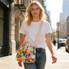 A young woman wearing a white t-shirt and jeans carries an insulated picnic lunch bag with a colorful pattern and cross-body 