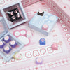 A collection of pink and purple silicone cat paw keycaps and heart caps displayed in a pink box and packaging.