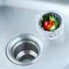 A white mesh filter containing fresh vegetables is placed inside a metal sink drain.