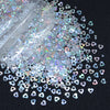 A close-up view of shiny holographic star sequins scattered on a dark surface.