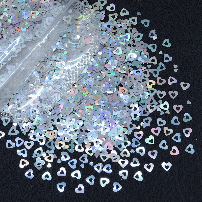 A close-up view of shiny holographic star sequins scattered on a dark surface.