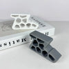 A gray heavy-duty non-slip door stopper wedge is shown next to a white plastic mold and a book.