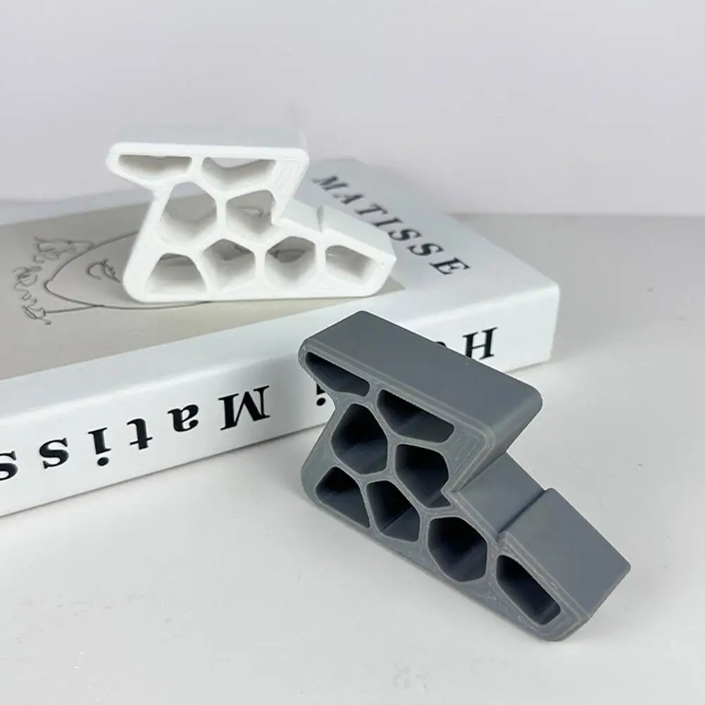 A gray heavy-duty non-slip door stopper wedge is shown next to a white plastic mold and a book.