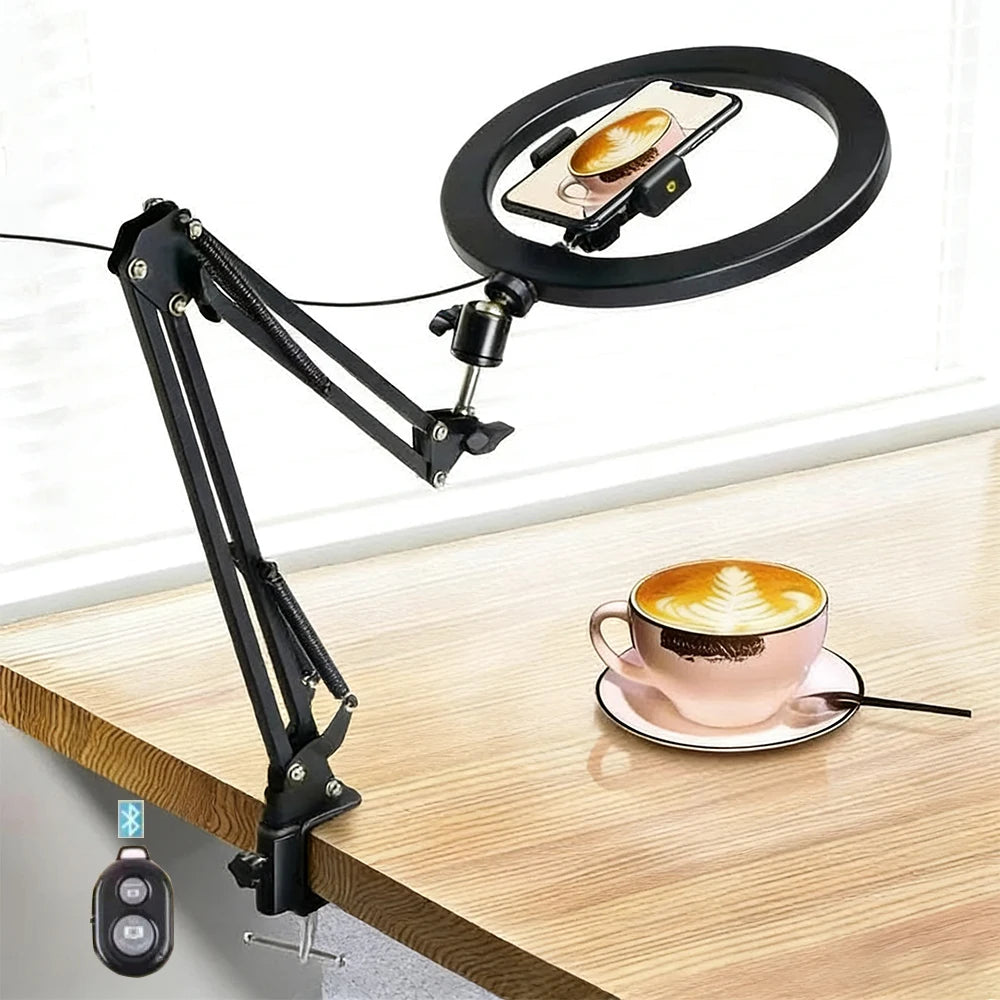 A black adjustable phone stand with an overhead light is positioned above a wooden table, illuminating a cup of coffee.