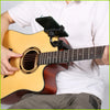 A person holds an acoustic guitar with an adjustable phone mount attached to the neck for hands-free viewing.