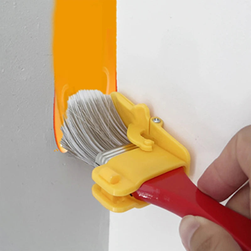 A hand holds a yellow precision edging paint brush with a corner trimmer, applying orange paint to a white wall.