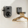 A modern, matte black retractable clothesline with a brass-colored hanging rack mounted on a wall.