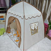A white foldable kids teepee play tent with brown fabric and ventilation windows set up indoors.