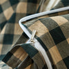 Close-up of a plaid duvet cover in earthy tones, showing the stitching and zipper detail.