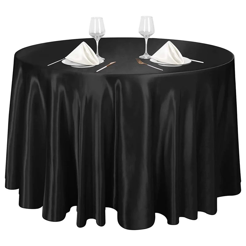 Elegant black satin round tablecloth set for events featuring glassware and silverware.