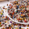 A bowl filled with mixed natural crystal gravel stones and gemstone chips of various colors and shapes.