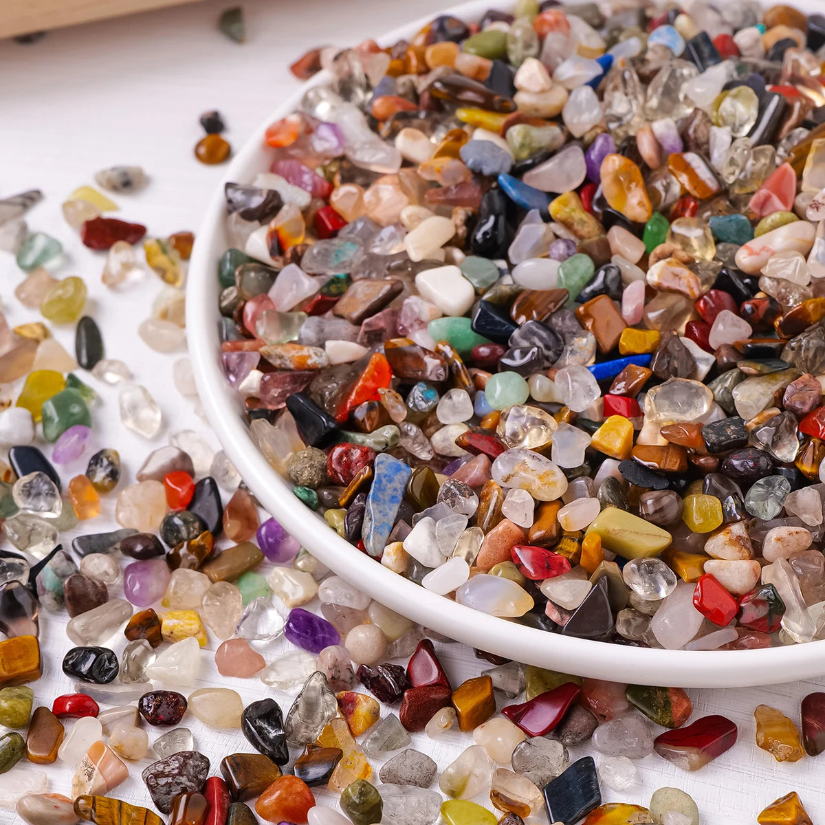 A bowl filled with mixed natural crystal gravel stones and gemstone chips of various colors and shapes.