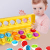 A baby is interacting with a yellow matching eggs Montessori toy that features various colored and shaped egg pieces.