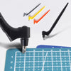 A black craft knife and several replacement blades in yellow, orange, and silver are shown above a grid ruler.