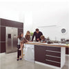 A modern kitchen counter features a stainless steel refrigerator and a wooden countertop with a white washing machine cover.