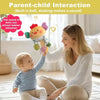 A mother interacts with a baby while holding a sensory toy that makes a sound.
