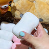 Eine Hand hält ein weißes Fidget-Spielzeug neben ein gelbes Plüschtier.