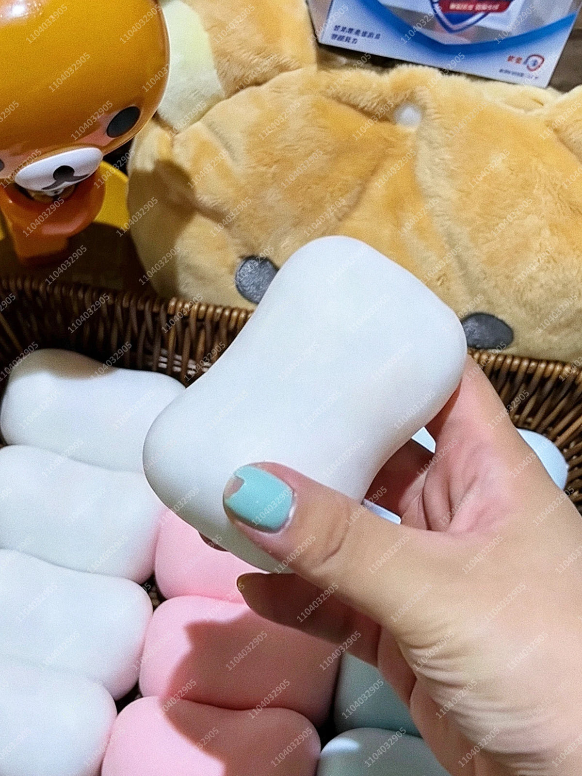 Eine Hand hält ein weißes Fidget-Spielzeug neben ein gelbes Plüschtier.